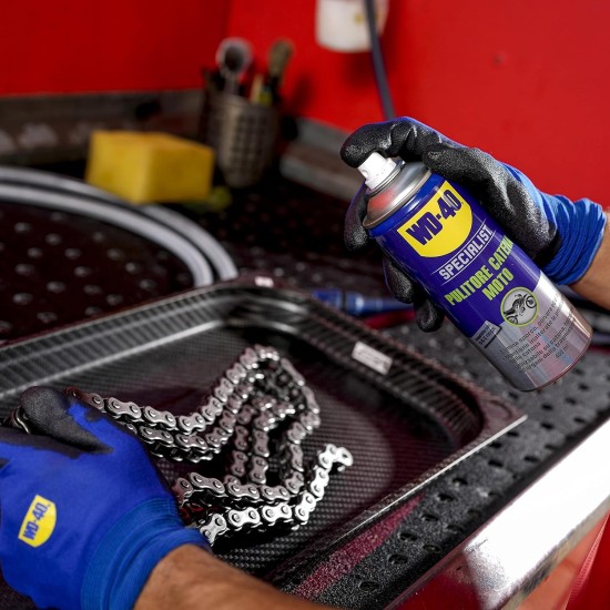 Wd40 Pulitore Catena  mentre viene spruzzato sulla catena smontato sopra un banco di lavoro