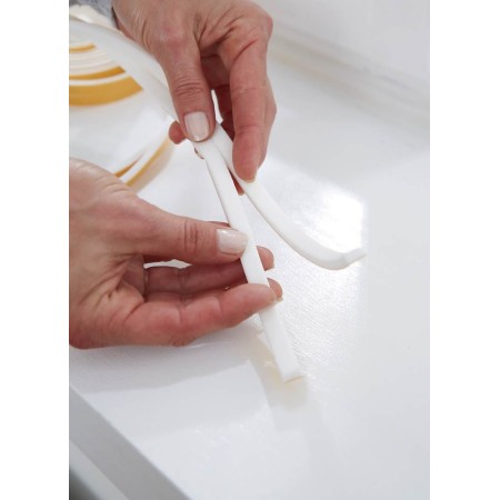 Mani che applicano una guarnizione in schiuma adesiva bianca Tesamoll su una superficie liscia