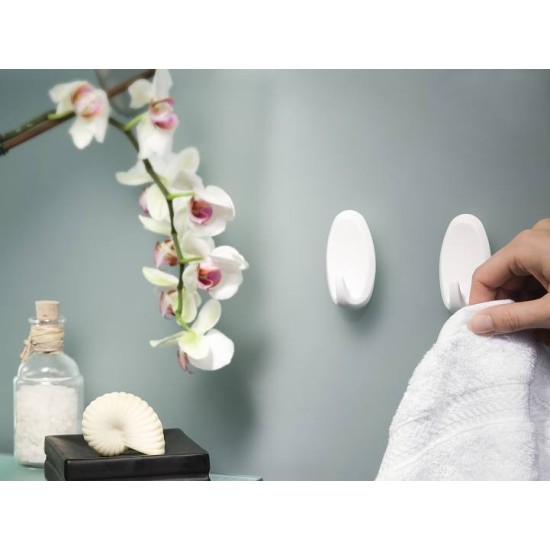 Mano che sta per appendere un asciugamano ai Ganci Powerstrips applicati in bagno.