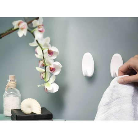 Mano che sta per appendere un asciugamano ai Ganci Powerstrips applicati in bagno.