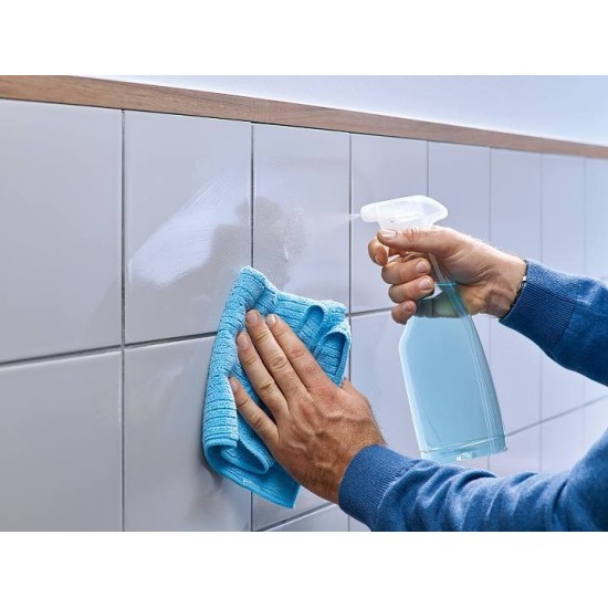 Mani che puliscono con un panno le piastrelle prima di applicare il Chiodo adesivo TESA.