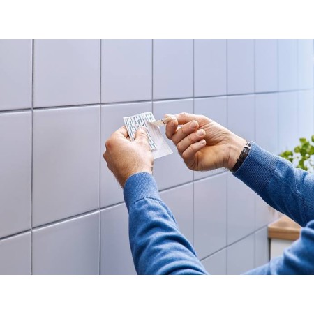 Mani che staccano la pellicola protettiva prima dell'applicazione del Gancetto Adesivo.